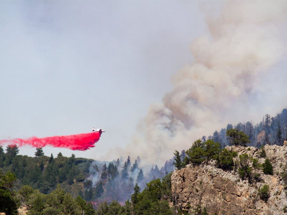 Firefighting aircraft drops red fire retardant over Grizzly Creek Fire