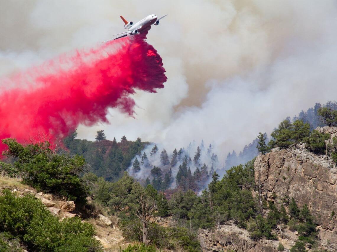 A DC-10 drops red fire retardant over Grizzly Creek Fire
