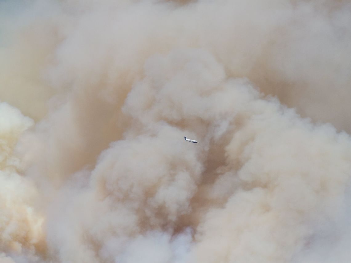 A small airplane flying near a Grizzly Creek Fire smoke column