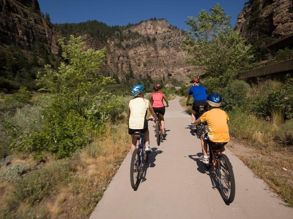 Four people ride bicycles on a scenic Glenwood Canyon Bike Path