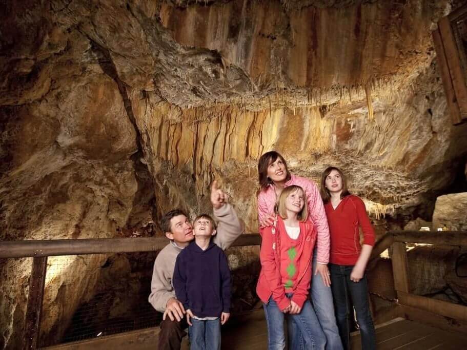 Parents and three children stand on a wooden platform inside a cave at Glenwood Caverns Adventure Park in Colorado
