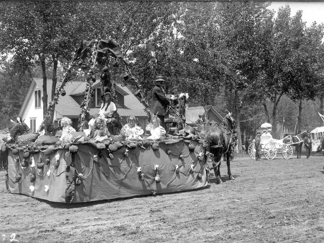 A historical black-and-white photo captures the delight of Strawberry Days with a decorated horse-drawn parade float