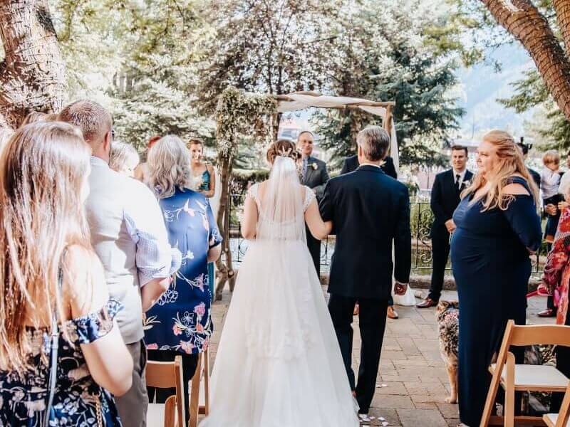 Bride being escorted down isle at Hotel Colorado