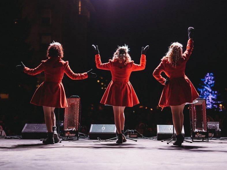Three female performers in red dresses on stage