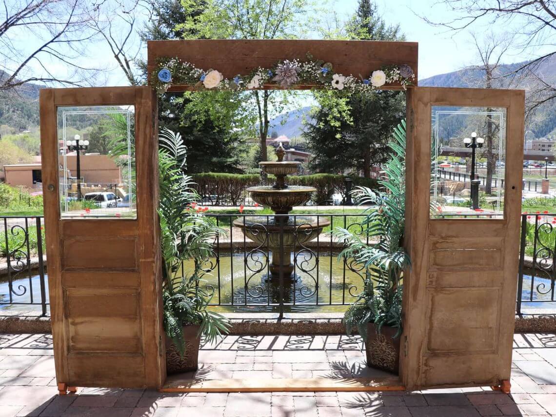 Decorative wooden door frame stands in front of a stone fountain for a Spring wedding in Glenwood Springs, Colorado