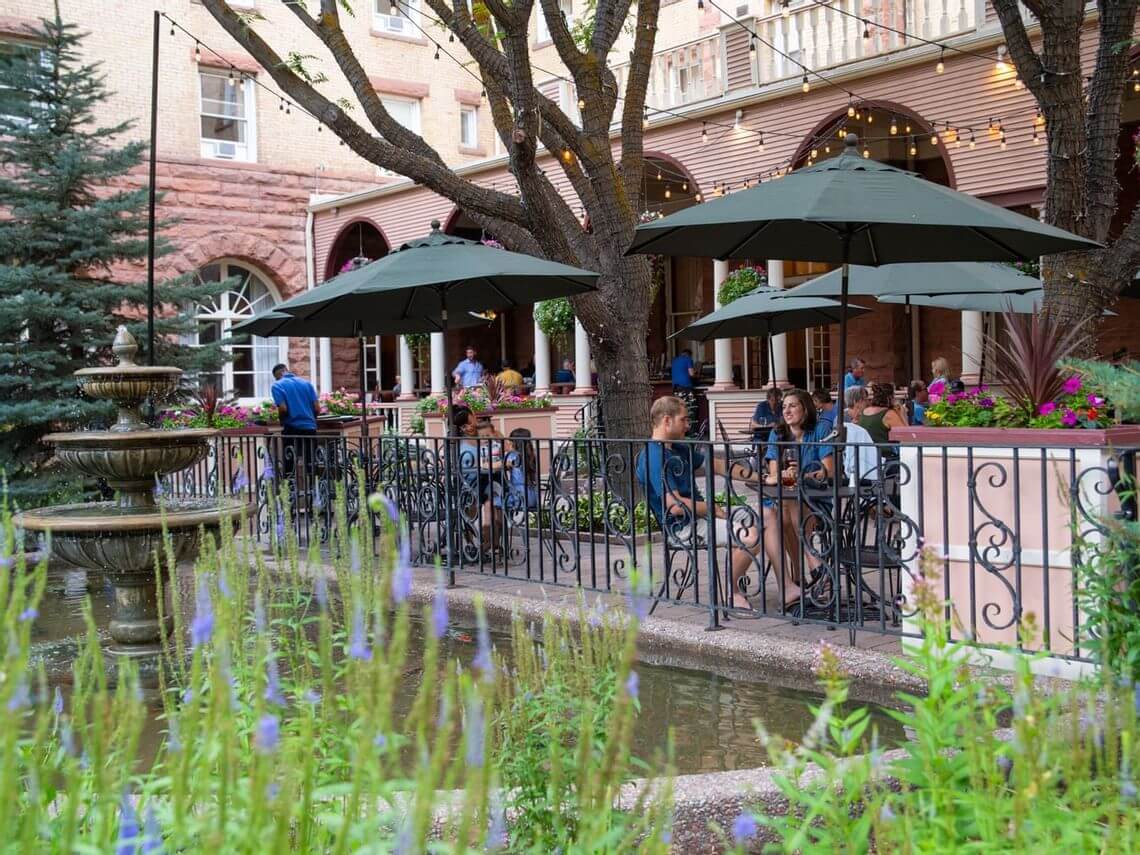 People enkoying a sunny day sitting at tables in the Hotel Colorado courtyard