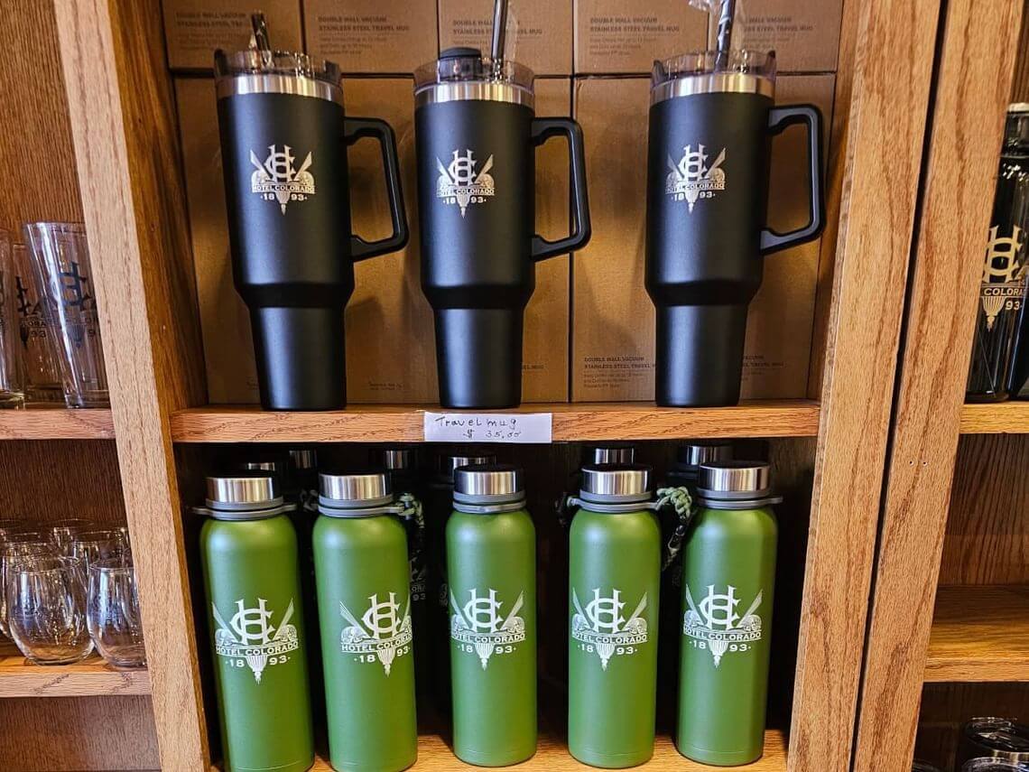 A wooden shelf stocked with Hotel Colorado Water Bottles