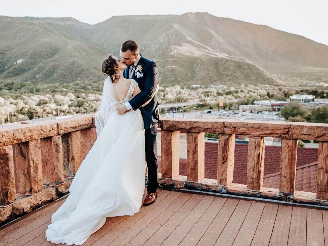 Bride and groom kissing on balcony after their wedding at Hotel Colorado