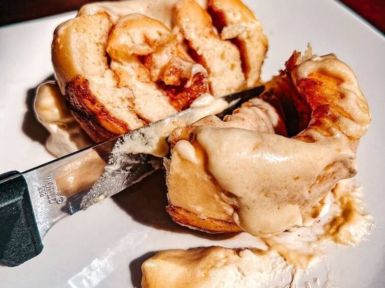 A close-up of a cinnamon roll being sliced