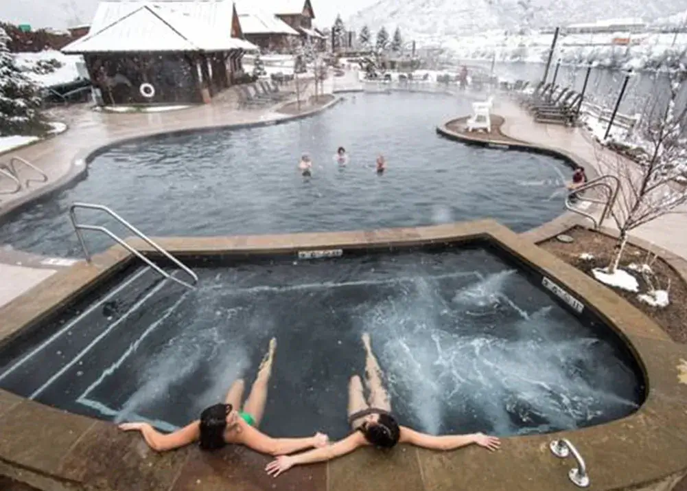 Two women relaxing in a hot tub pool in winter at Iron Mountain Hot Springs