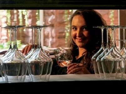 A woman smiles while pouring a glass of wine at Hotel Colorado