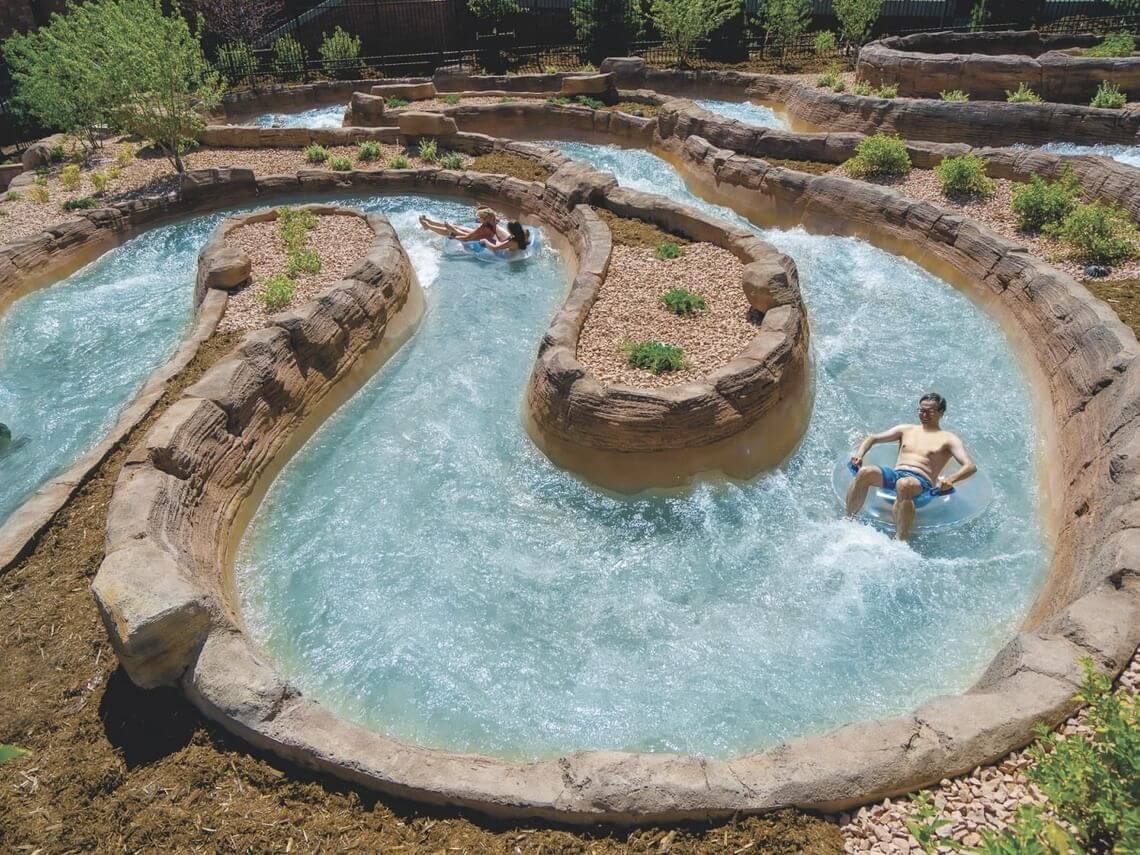 Adults meandering down Shoshone Chutes on inflatable tubes at Glenwood Hot Springs Splash Zone