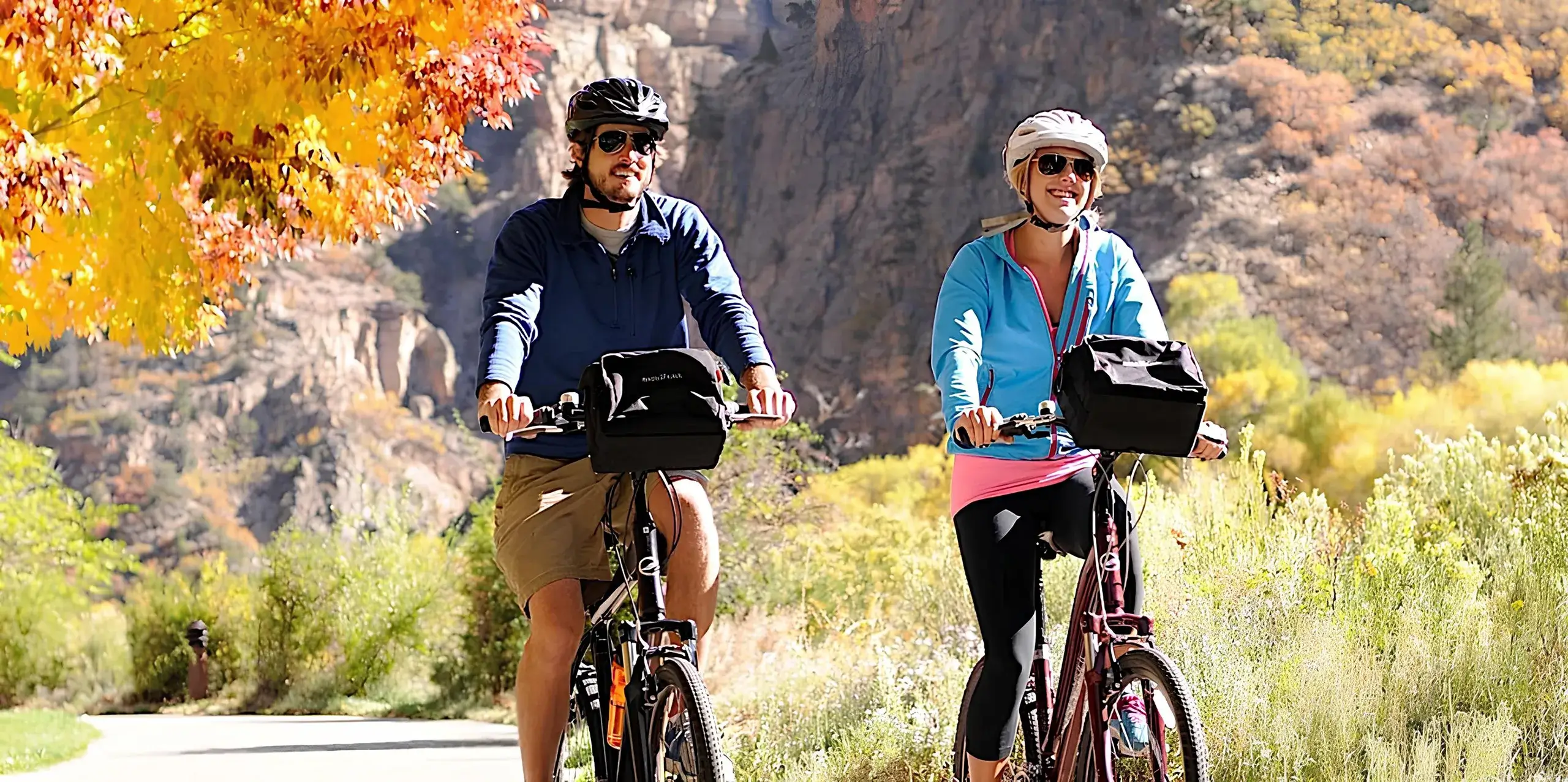A man and woman leisurely biking on a pathway through Glenwood Canyon
