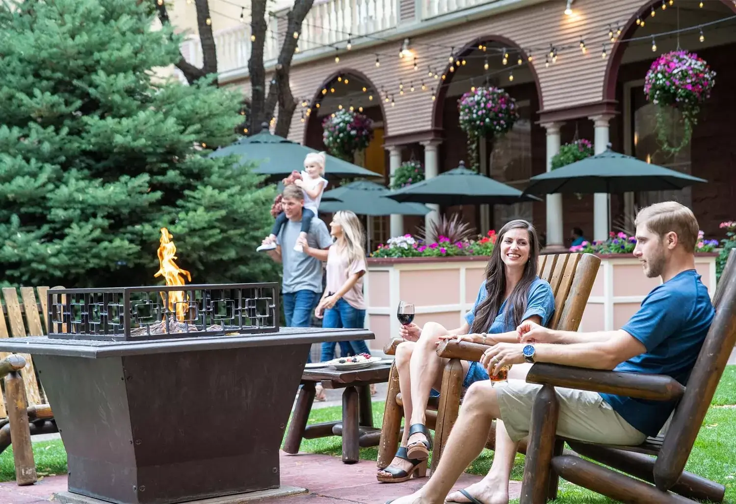 A couple sitting by a lit fire pit at Hotel Colorado in Glenwood Springs