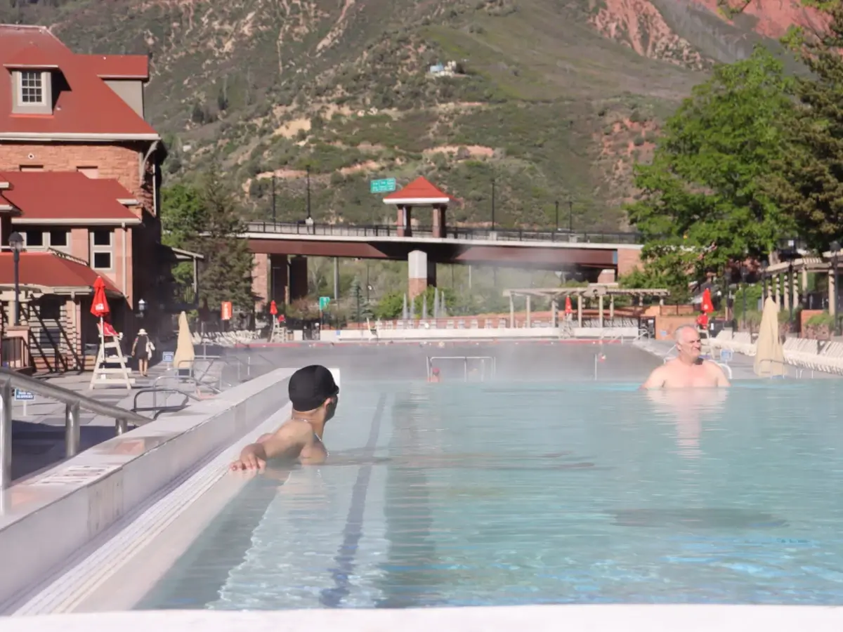 Two men enjoying the views at the infinity-edge Sacred Waters bath pool at Glenwood Hot Springs