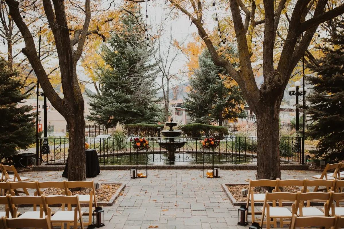 Rows of wooden chairs facing a decorative fountain for a Fall outdoor wedding at Hotel Colorado