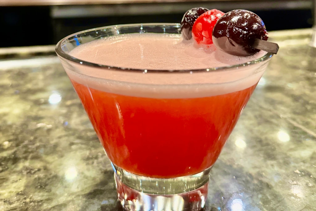 The Driftwood is a vibrant red cocktail in a martini glass.