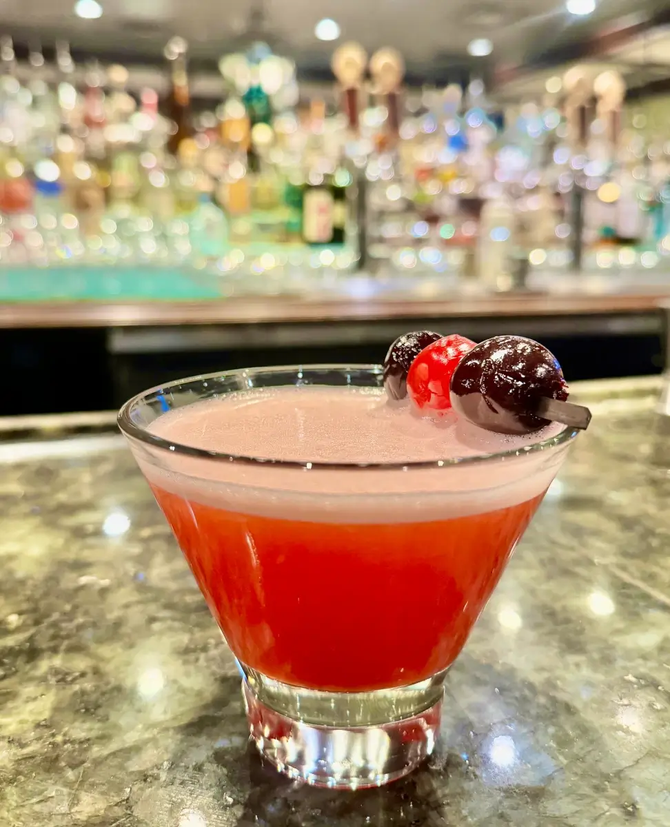 The Driftwood is a vibrant red cocktail in a martini glass.